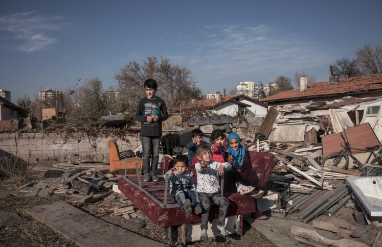 Uygurlu ve Suriyeli ailelerden çocuklar, Taufeeq’in evinin önünde bir hurda yığını üzerinde bir fotoğraf için birlikte poz veriyor